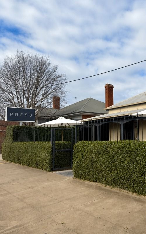 An outdoor cafe with hedges and iron gate